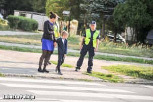 policjantka, kobieta z dziecikiem przed przejściem dla pieszych