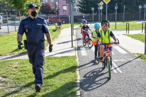 policjant asystuje dzieciom podczas jazdy na rowerze