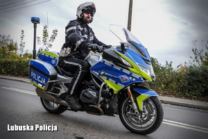 policjant na motocyklu jedzie na drodze w rejonie cmentarza